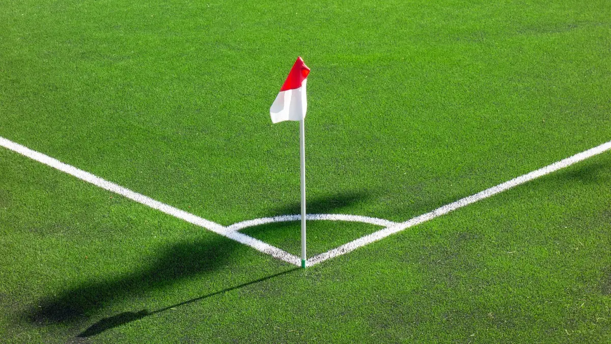 Banderín de córner sobre césped con las líneas del cuarto de circunferencia marcadas en blanco