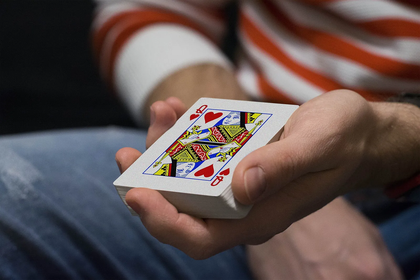 Mano sosteniendo una baraja de cartas con la reina de corazones a la vista