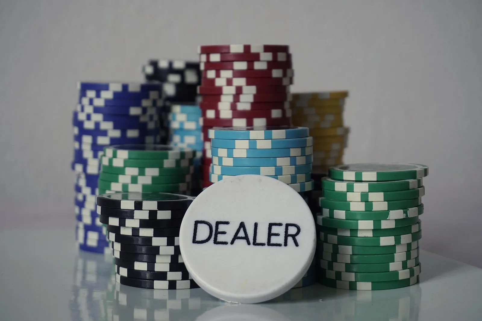 Columnas de fichas de casino junto a un botón blanco de repartidor sobre fondo claro