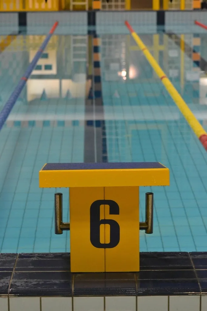 Poyete de salida amarillo con el número seis junto a una piscina cubierta con corcheras